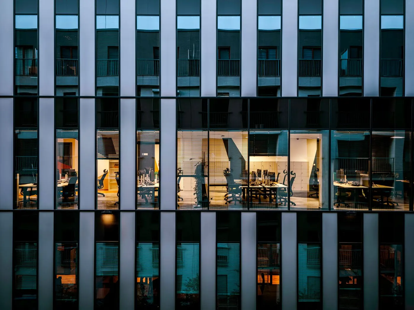 A modern glass office building lit at dusk