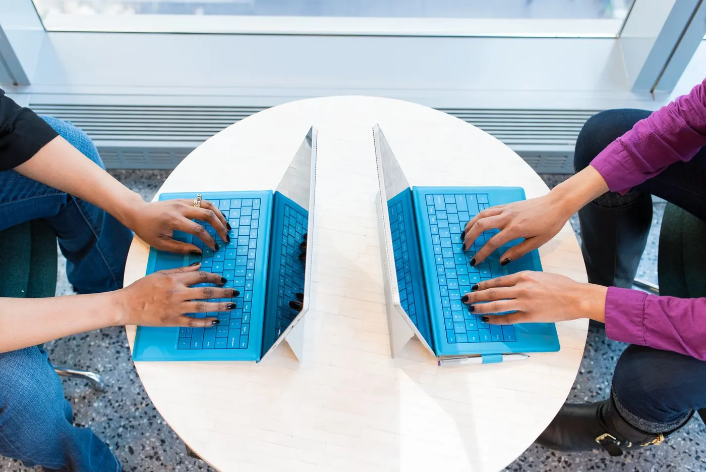 Colleagues working together across laptops at a shared desk